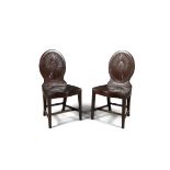 A PAIR OF GEORGE III MAHOGANY HALL CHAIRS, the oval backs with starburst fluting on panelled