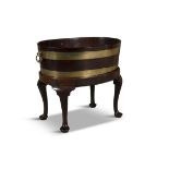 A GEORGE III MAHOGANY BRASS BOUND OVAL WINE COOLER with brass banding and twin handles raised on