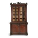 A VICTORIAN PITCH PINE TWO DOOR GLAZED CABINET, the moulded cornice surmounted by a carved harps