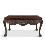 AN IRISH GEORGE III STYLE MAHOGANY SIDE TABLE of typical form, the shaped frieze centred with a