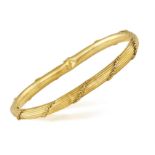 A GOLD BRACELET, the hinged bracelet with reeded detailing throughout with foliate decorations,