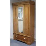 A Victorian pine wardrobe with a moulded cornice, enclosed by a rectangular mirror door to centre