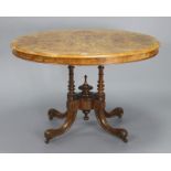 A Victorian burr-walnut oval tilt-top dining table on four turned & fluted supports & carved splay