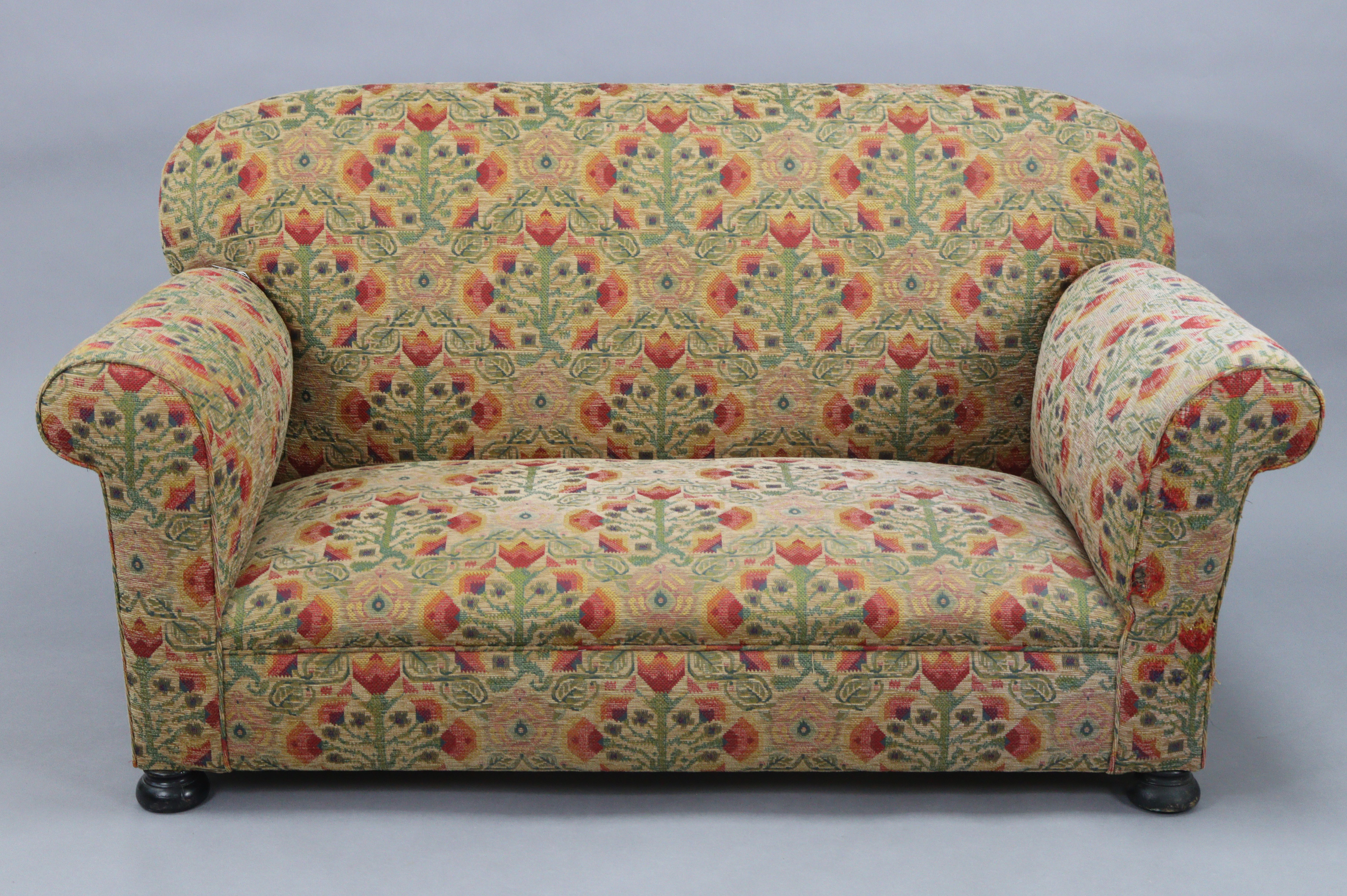 An early 20th century drop-end two-seater settee with rounded back, scroll-arms & sprung seat