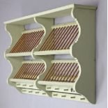 A pale green painted wooden wall-mounted plate rack with shaped end supports, 50” wide x 29½” high x