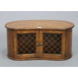 A walnut-finish kidney-shaped table top cabinet, enclosed by pair of wrought-iron grille doors,