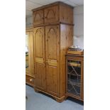 A pine wardrobe enclosed by a pair of fielded panel doors, on a shaped plinth base, & with a box-top