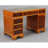 A reproduction yew wood pedestal desk, inset gilt-tooled green leather fitted three frieze