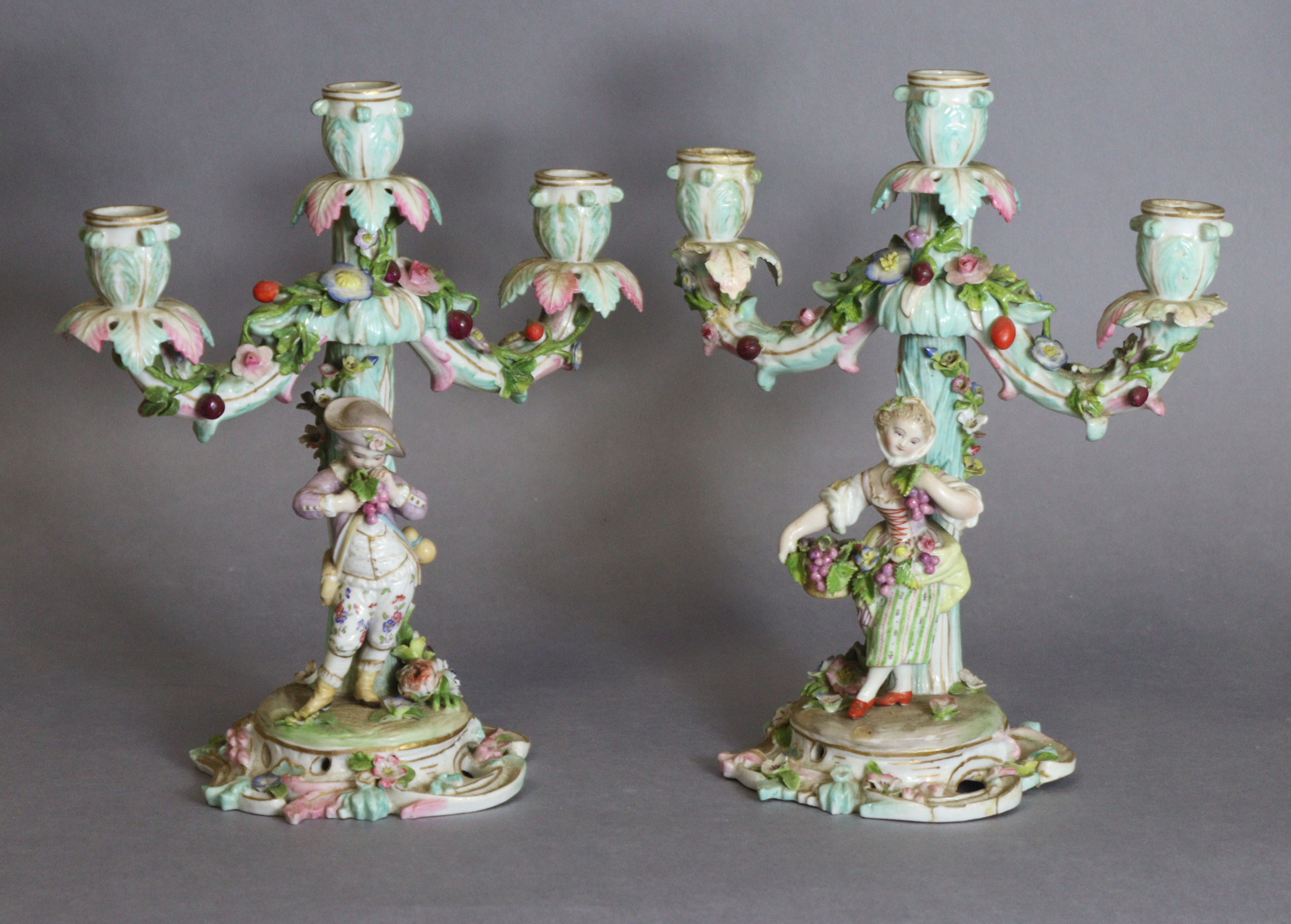 A pair of Meissen porcelain three-branch floral-encrusted candelabra, one with a girl holding a