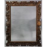 A large carved oak picture frame with wide leaf-scroll border & two carved wooden crests, 42.25”