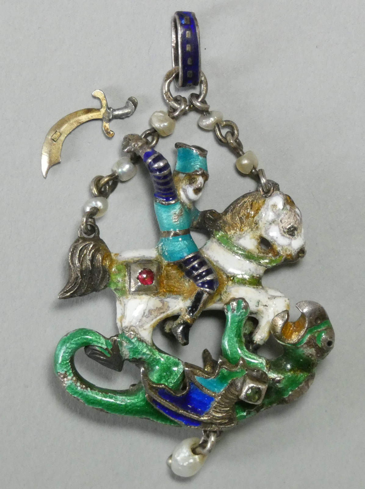 An Austro-Hungarian enamelled white metal pendant depicting St. George slaying the Dragon,