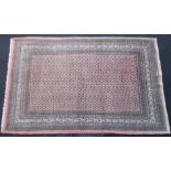 A Persian carpet of pink ground with all-over repeating geometric design & multiple narrow