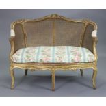 A 19th century French carved giltwood frame small sofa with rounded cane back, loose cushion