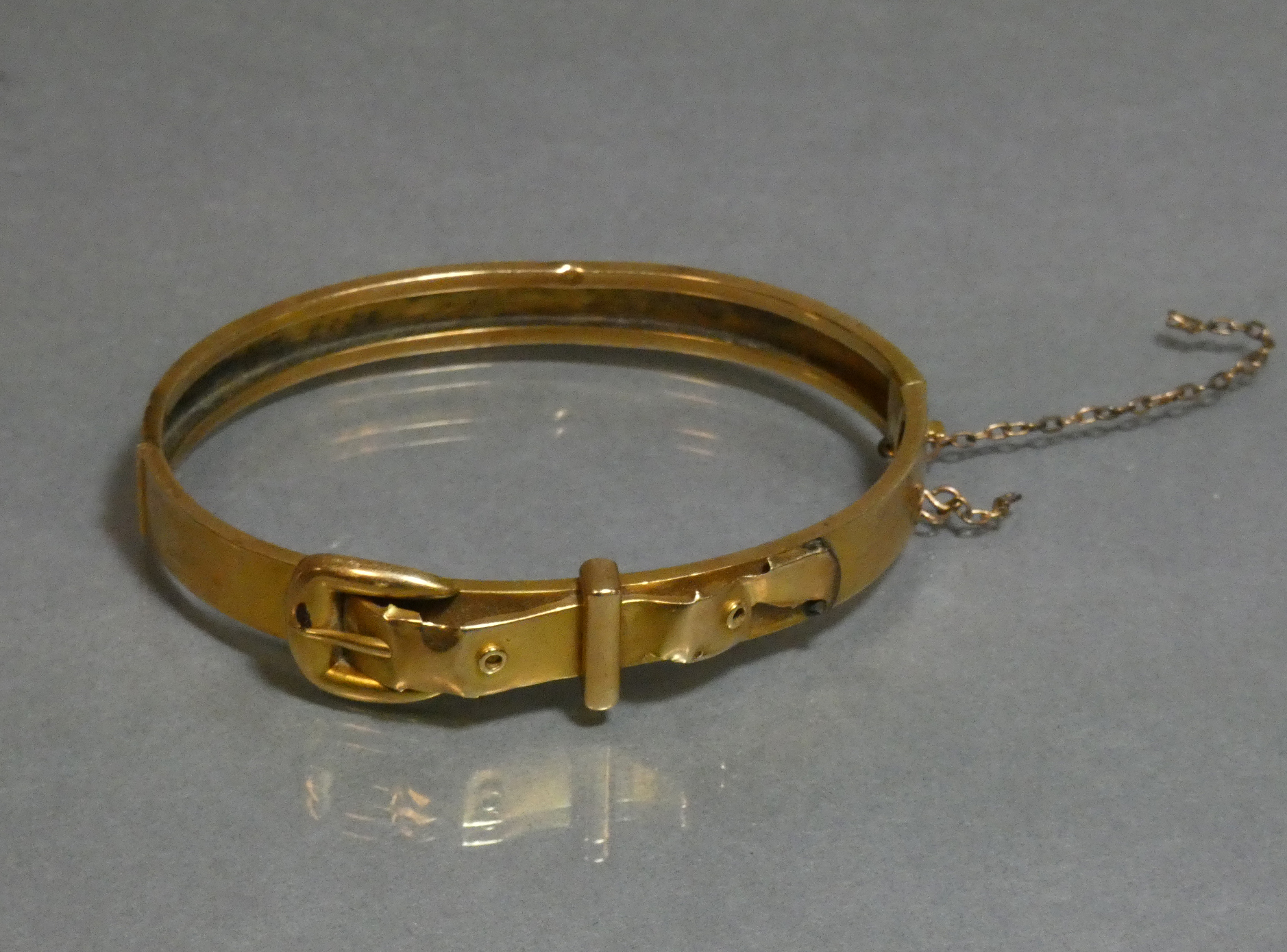 A yellow metal stiff hinged bangle of belt & buckle design, marked “14” (8.8g; w.a.f.)