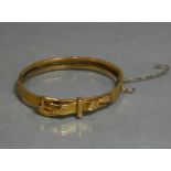 A yellow metal stiff hinged bangle of belt & buckle design, marked “14” (8.8g; w.a.f.)