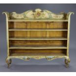 A painted standing open bookcase of cream ground with all-over floral decoration & blue scroll