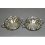 A pair of Edwardian silver circular two-handled sweetmeat dishes with embossed swags to the