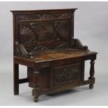 An oak small settle with profusely carved Elizabethan-style decoration, having scroll arms, box-