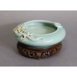 A Chinese porcelain shallow bowl of squat round form & pale celadon glaze, a dragon in relief to one