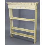 A set of light cream painted wooden wall shelves with a moulded frieze, & fitted three open shelves,