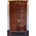 A 17th century-style tall oak wardrobe with a moulded cornice, enclosed by a pair of panel doors