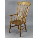 A Victorian beech lath-back elbow chair with a hard seat, & on turned legs with spindle stretchers.