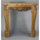 A continental-style beech small serpentine-front fire-surround with a carved frieze & on carved