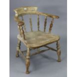 A spindle-back captain’s chair with a hard seat, & on turned legs with turned stretchers.