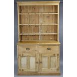 A pine dresser, the upper part fitted three open shelves & with panelled back, the base fitted two