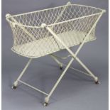 A vintage white painted wrought-iron fold-away cot, on square legs with ceramic castors, 42” wide.