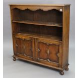 An early 20th century Jacobean-style oak bookcase, fitted with an open shelf above a cupboard