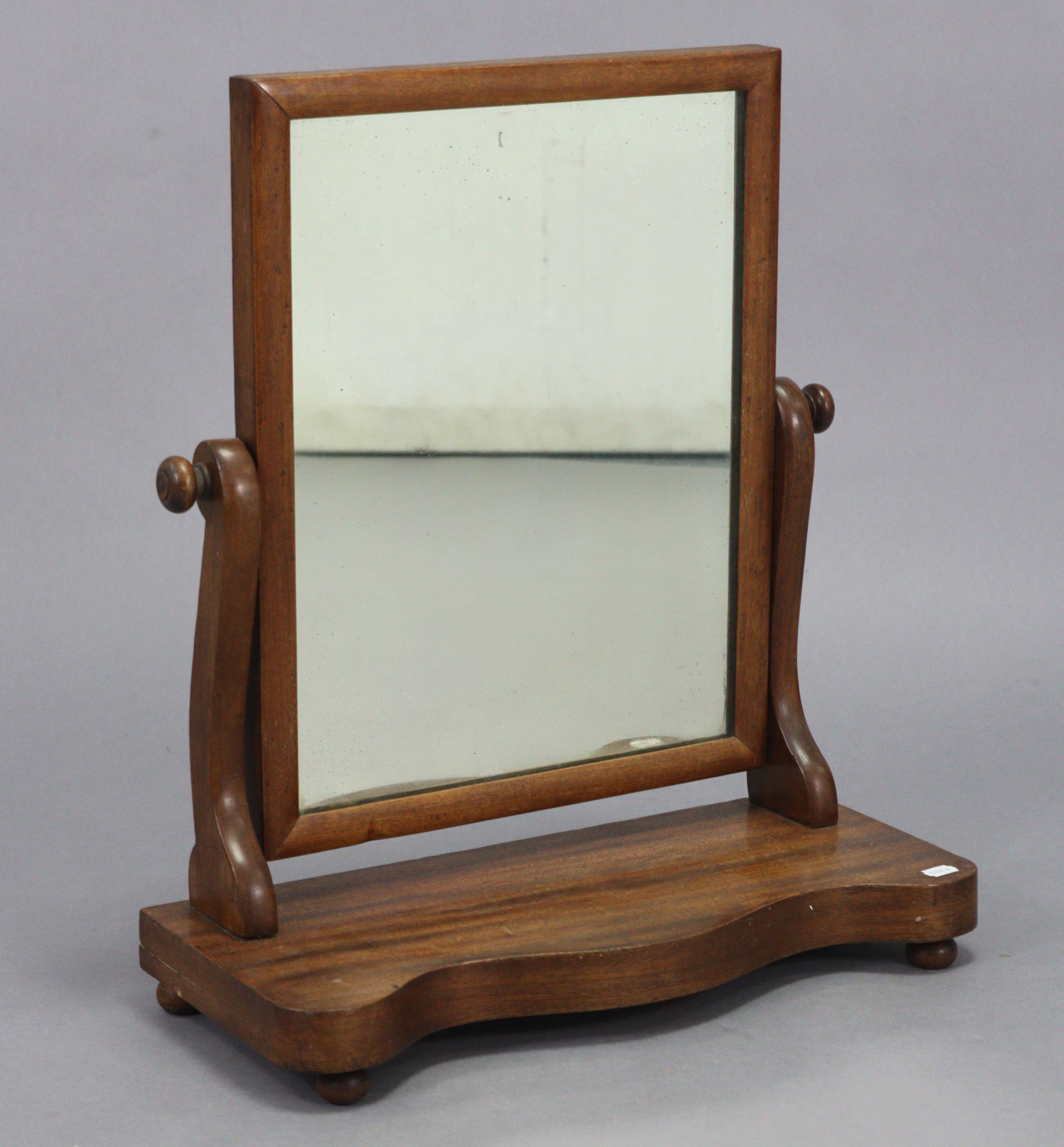 A Victorian mahogany rectangular swing toilet glass on scroll supports, & on serpentine-front