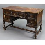 An early 20th century Jacobean-style oak breakfront kneehole writing desk, inset tooled crimson