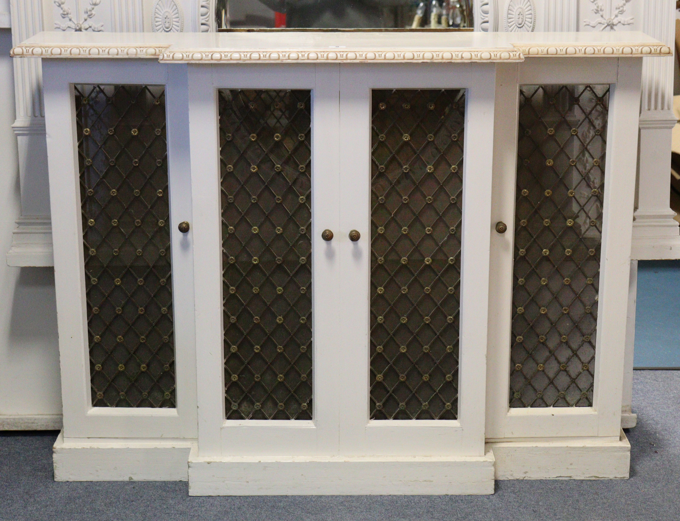 A white & cream painted wooden break-front radiator cover with moulded edge enclosed by two pairs of