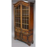 An early 20th century Jacobean-style oak tall bookcase with shaped top, having three adjustable