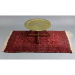 An eastern engraved brass circular tray-top occasional table on a folding hardwood stand, 29” diam.,