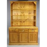 A pine dresser, the upper part with three open shelves & panelled back ,the base fitted three frieze