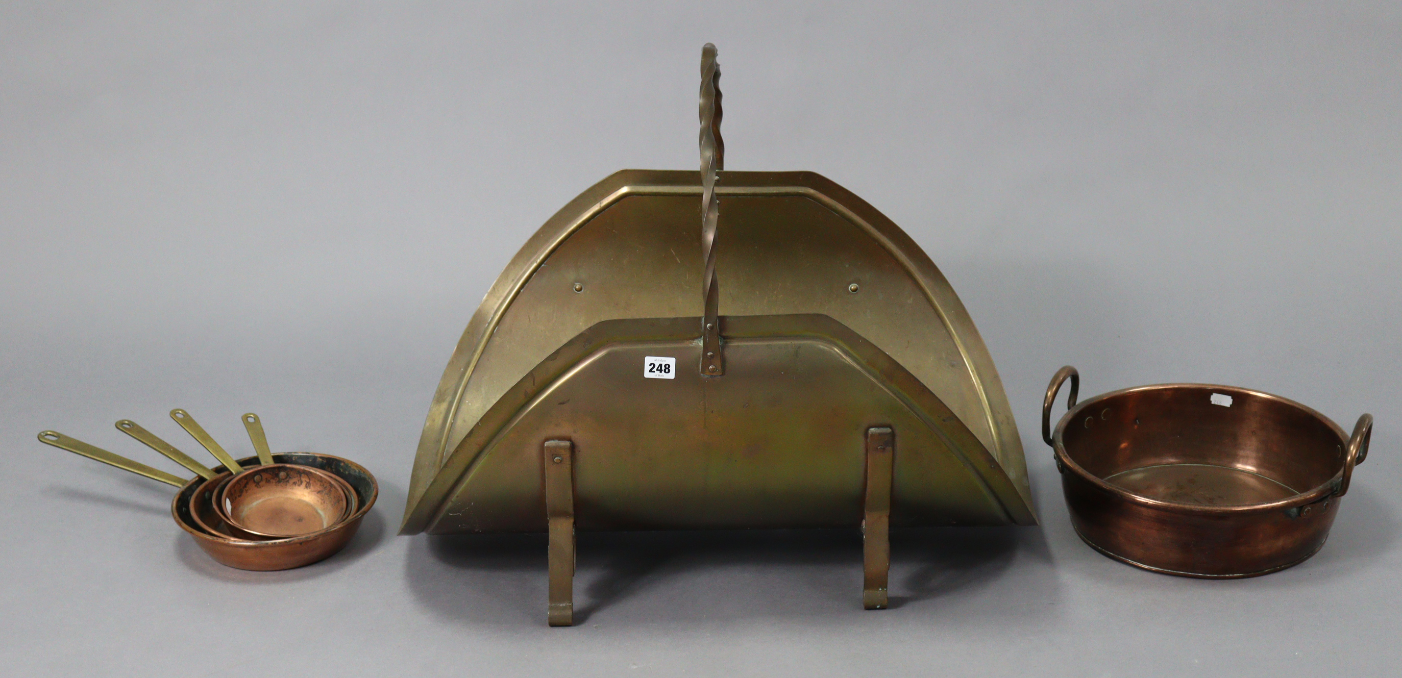 A brass log carrier with a wrought-iron overhand handle, 27½” wide x 24” high; four copper