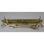 A brass fender, 45” long; together with a pair of brass fire dogs; & a set of four brass fire