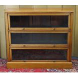 An Edwardian oak standing bookcase enclosed by three glazed ‘up-&-over’ sliding doors in the Globe