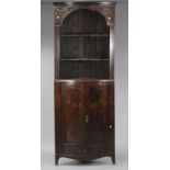 A late 18th century mahogany tall standing corner cupboard with applied husk-swag & ribbon-bow