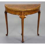 An early/mid-20th century burr walnut veneered card table with demi-lune fold-over top inset green