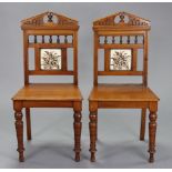 A pair of Victorian mahogany tile-back hall chairs with blind-fret carving, hard seats & on ring-