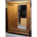 A late 19th/early 20th century Continental fruitwood wardrobe enclosed by a bevelled mirror panel