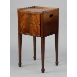 A George III style mahogany bedside cupboard with shaped tray-top, ebonised inlay & pierced side