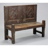 A carved oak hall bench constructed from 17th century panels with stylised decoration, on square