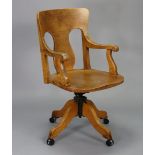 An early/mid-20th century oak swivel desk chair with splat-back, open arms & hard seat, on four
