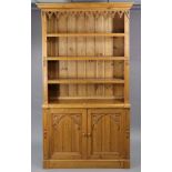 A pine dresser in the gothic-style, fitted three open shelves to the upper part, a pair of panel