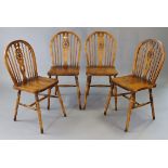 A set of four wheel-back dining chairs with hard seats, & on turned legs with spindle stretchers.