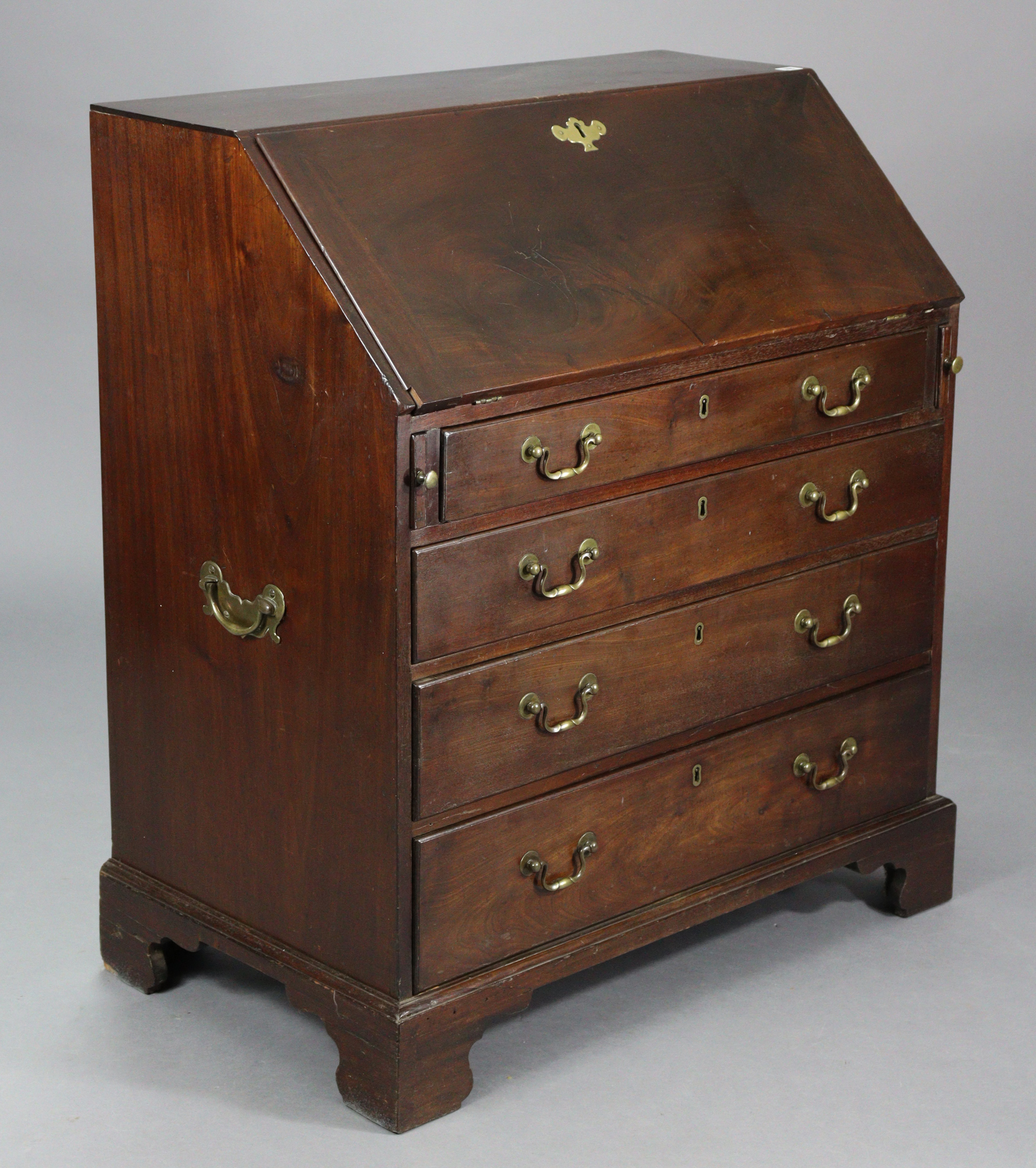 A Georgian mahogany bureau with a fitted interior enclosed by a fall-front above four long graduated